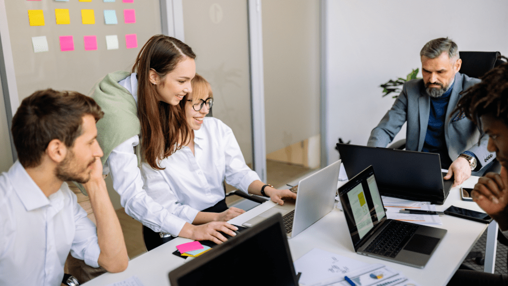 Equipo de trabajo reunido en una oficina, colaborando frente a varios portátiles durante una reunión.