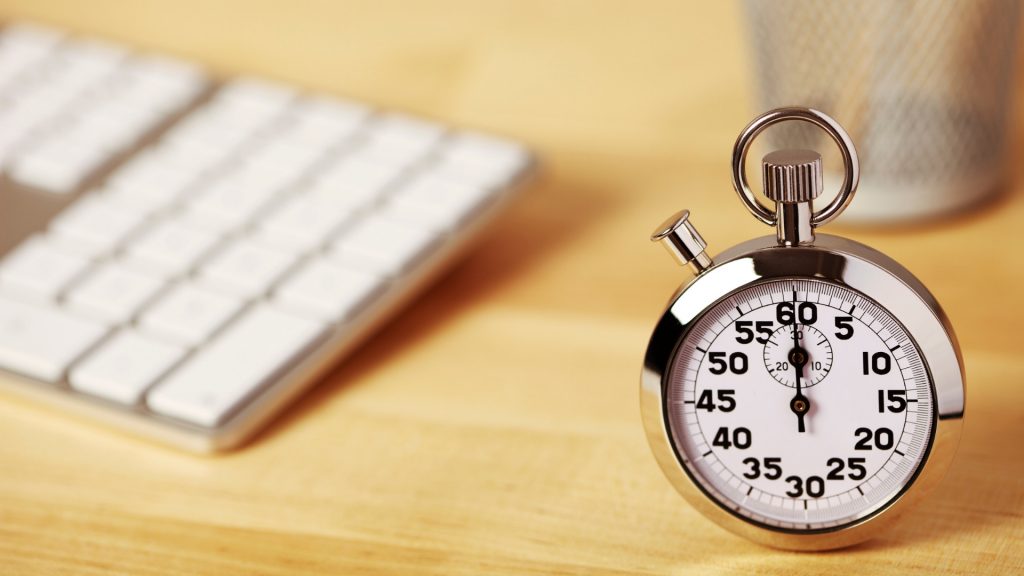 Mejorar la eficiencia laboral como posibilidad de generar beneficios para la empresa. En la imagen encontramos un reloj sobre una mesa de oficina, simulando la optimización del tiempo como característica de la buena eficiencia laboral.