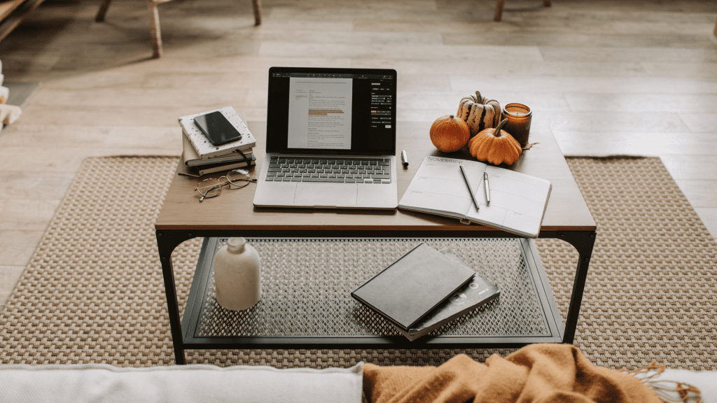 Productividad laboral. Encontramos una mesa con documentos, un ordenador y unas gafas, haciendo referencia a la productividad de un trabajador.
